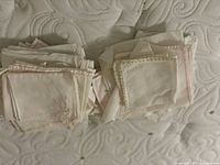 two piles of small white/ivory linens, some with lace trim and pink stripes