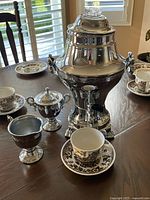 Group view of urn, kettle, sugar bowl, open bowls on table