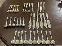 Assorted flatware groups arranged on table: forks, knives, servers, small spoons, teaspoons