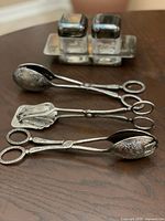 Full lot: three pastry tongs in foreground, condiment set in background