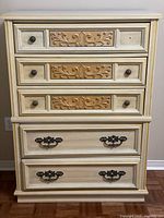 Front view of five-drawer French Provincial dresser showing carved drawer fronts and hardware