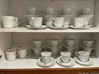 Cabinet shelves showing multiple white ribbed cups paired with saucers