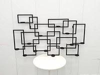 Front view of entire wall candle holder showing geometric frame and all 14 candle plates