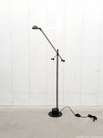 Full view of black counterbalance floor lamp showing base, stem, arm and power cord