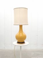 Full view of yellow gourd-shaped lamp with shade on stand