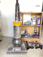 Dyson DC66 vacuum with attachments, cleaning agents and manual on shelving unit