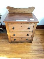 Front view of solid wood 3-drawer chest with shaped backsplash and round knobs