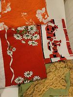 Stack showing orange floral, red daisy, utensil motif, and lace pieces