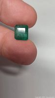 Emerald held between fingers showing size and color