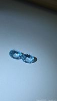 Front view of both blue topaz gemstones on neutral background
