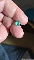 Emerald held between fingers showing size and color