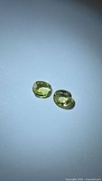 Two cushion cut yellow gemstones on white background