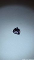 Triangular gemstone under overhead light showing overall shape and color