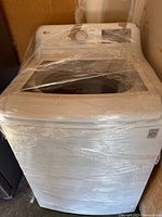 Front three-quarter view of LG washer wrapped in plastic