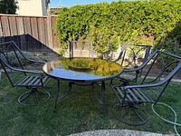 Overall view of glass table with five metal chairs