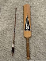 Full view of cricket bat and arrow side by side