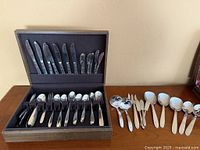 Overall view of flatware in wood case with additional serving pieces laid out