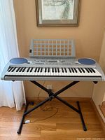 Front view of Yamaha PSR-275 keyboard on X stand with music rest attached