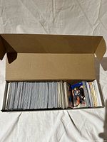 Open cardboard storage box showing large quantity of sleeved baseball cards
