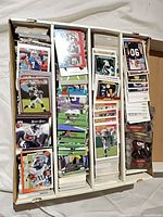 Open four-row card box filled with sorted football cards, some cards in rigid cases