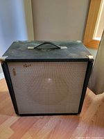 Front view of black guitar amplifier with grey grille and handle visible