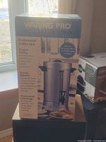 Front of boxed Waring Pro coffee urn displaying product image and features