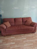 Front view of rust sofa with two polka dot pillows
