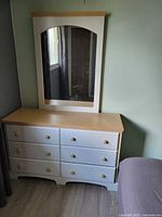 Front view of dresser showing six drawers, wood top, knobs, and matching mirror