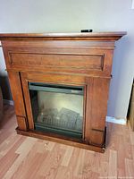 Full view of wood mantel electric fireplace with remote on top