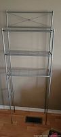 Full view of tall metal wire shelving unit with three shelves and open lower section