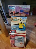 Stacked retail boxes for Holmes Warm Mist Humidifier, Hot Shot handheld steam cleaner, Perfect Edger refillable paint roller