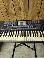 Front view of Yamaha PSR-220 keyboard on X-stand showing control panel and keys