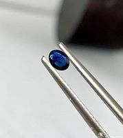 Close-up of one sapphire held by tweezers