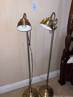 Full view of both brass floor lamps with domed shades