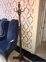 Full view of wood coat rack beside chairs