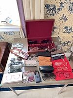 Tabletop view showing all eyewear pairs, cases, Burberrys box and wooden display case
