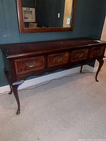 Full view of dark wood console table showing four drawers and cabriole legs
