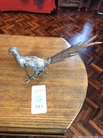Side view of metal pheasant figurine on wooden surface