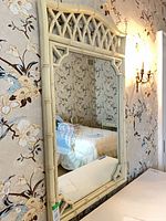 Front view of off-white faux bamboo vanity mirror on wall