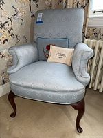 Full view of one blue upholstered arm chair with pillow