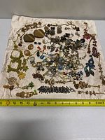 Full view of mixed jewelry spread on fabric with measuring tape for scale