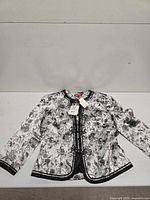 Front view of silver floral satin jacket laid flat showing overall design and trim