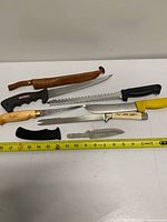 All six knives laid out with tape measure for scale