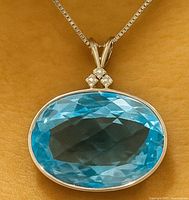 Front view of pendant showing blue topaz, diamond accents, bail