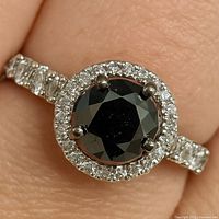 Close-up of ring on finger showing black diamond and CZ halo