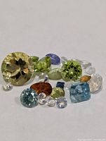 Group of loose faceted gemstones on white background showing variety of sizes and colours