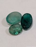 Close-up of three oval emerald gemstones on white background
