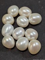 Group of twelve white baroque pearls on dark background