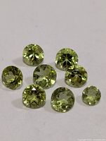 Close-up of eight green faceted peridot stones on white background