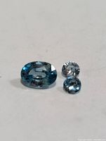 Oval and two round blue zircon gemstones on neutral background